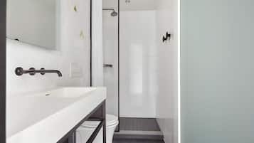 A modern bathroom with a white sink, a glass shower enclosure, and a toilet.