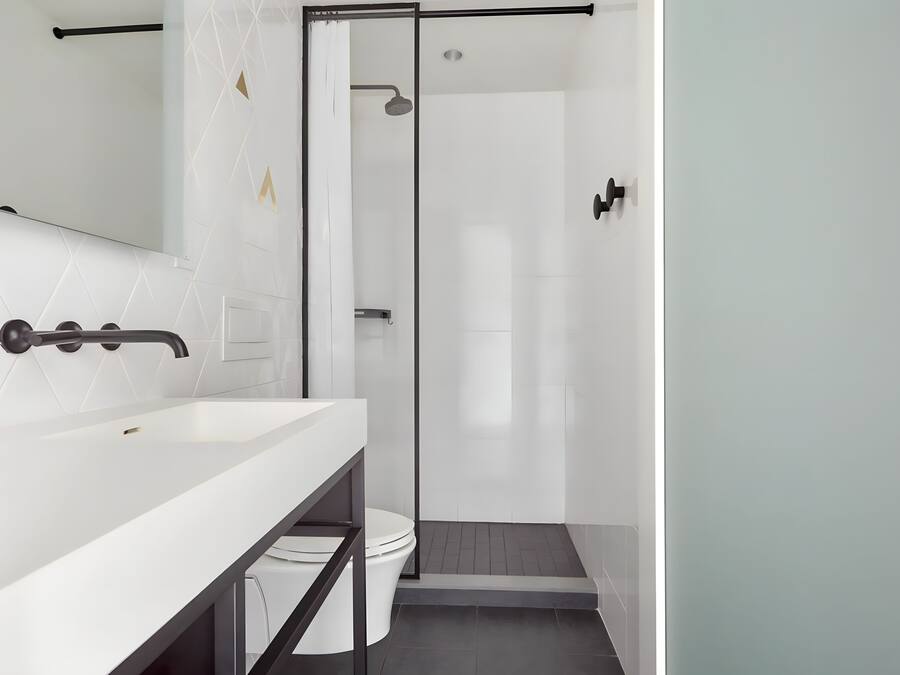 A modern bathroom with a white sink, a glass shower enclosure, and a toilet.