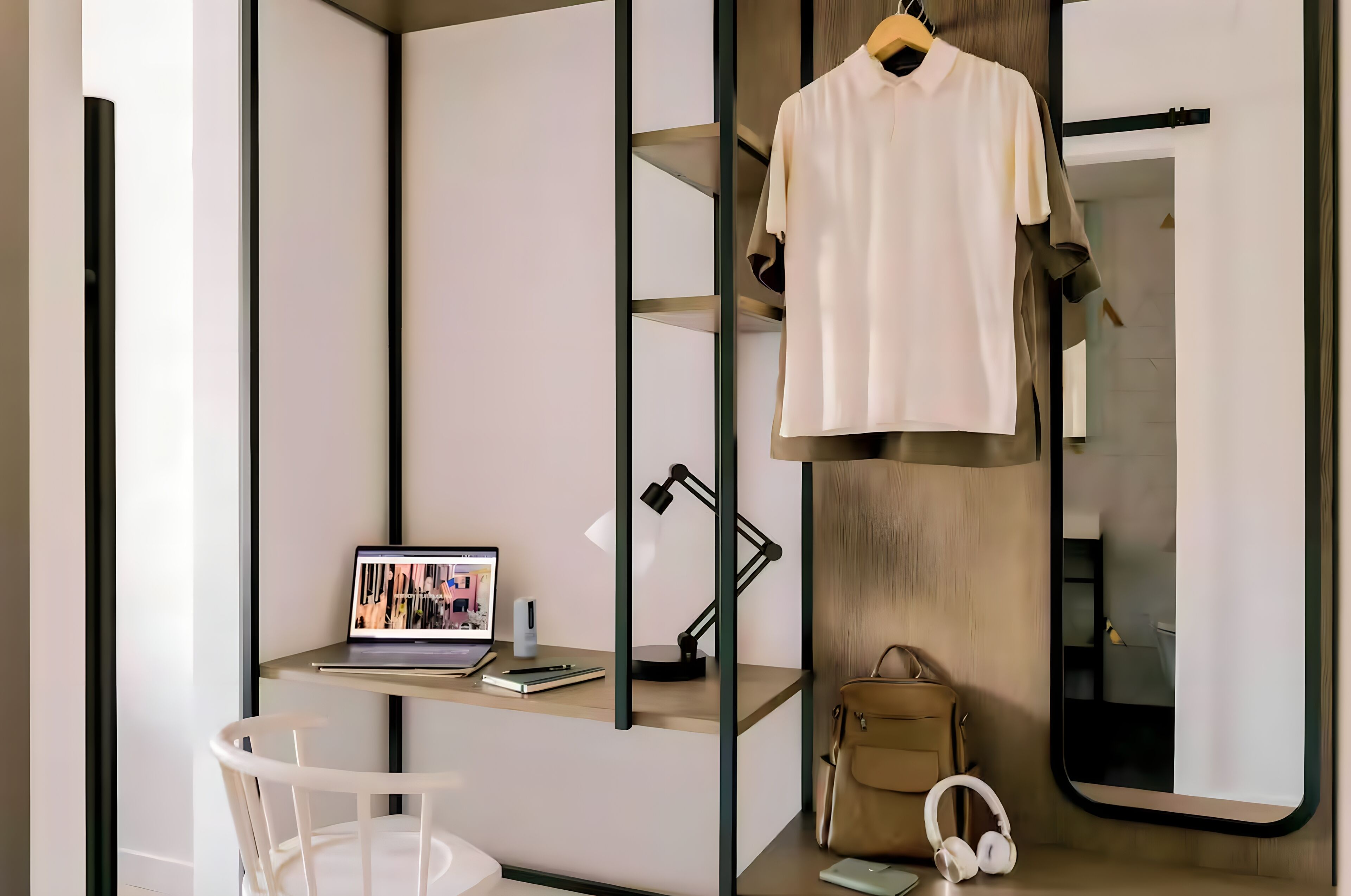 Ein modernes Zimmer mit Schreibtisch, Laptop und Kleiderhaken.