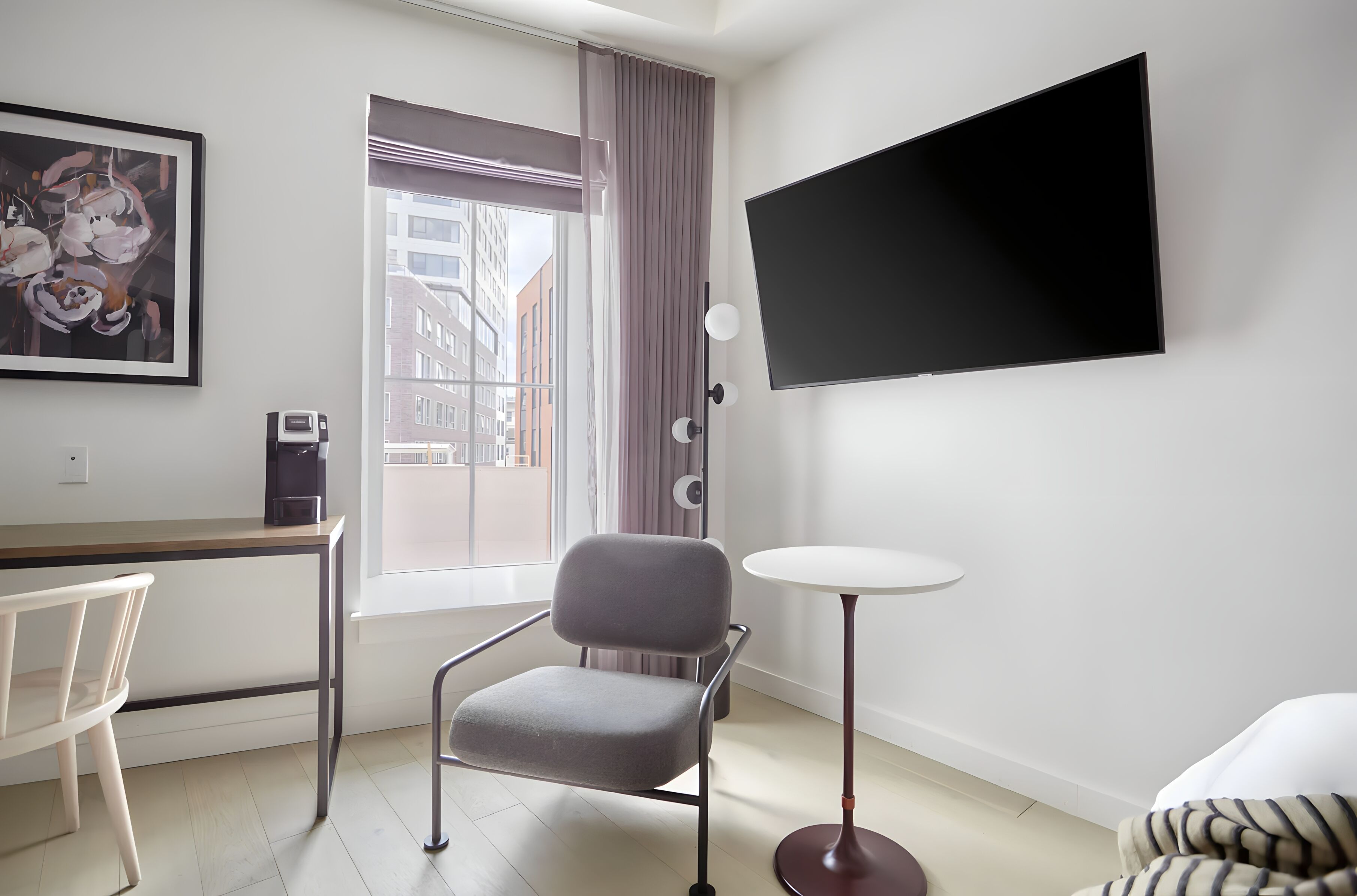 Ein modernes Hotelzimmer mit Schreibtisch, Stuhl und einem wandmontierten Flachbildfernseher.