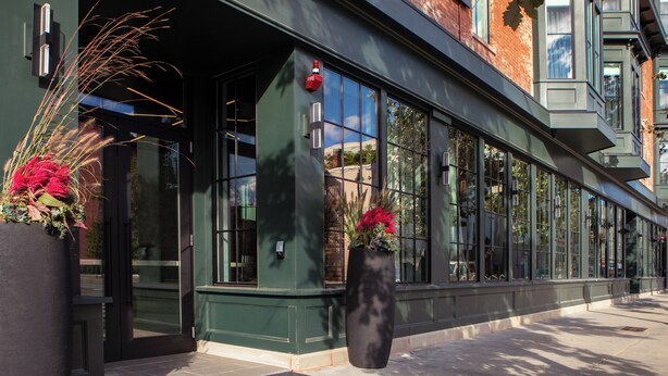 A building entrance with a doormat, large windows, and potted plants. - Lark Hotels 907 Main (Cambridge)