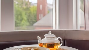 A round table with a teapot and biscuits by a window with a view of a building with a tower. - Lark Hotels 907 Main (Cambridge)