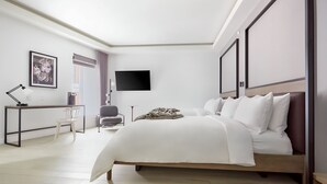 A modern bedroom with a large bed, a desk with a chair, a flat-screen TV, and a framed picture on the wall. - Lark Hotels 907 Main (Cambridge)