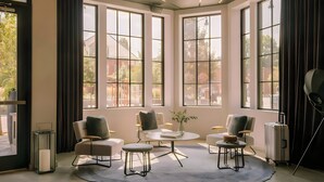 A modern room with large windows, a round table, and four chairs. - Lark Hotels 907 Main (Cambridge)