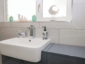 A bathroom with a white sink, a mirror, and a window. - Mables (Wigton)