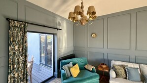 A room with a teal sofa, a white sofa, a wooden side table, and a chandelier. - A beautifully refurbished family home on Flexbury Park Road. (Cornwall)