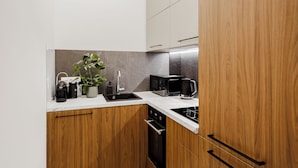 Une cuisine moderne avec des meubles en bois, un plan de travail en marbre, un évier, une machine à café et un four à micro-ondes.