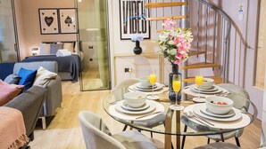 Ein modernes Wohnzimmer mit einem Esstisch aus Glas, gedeckt für das Frühstück, einer Couch und einer Treppe.