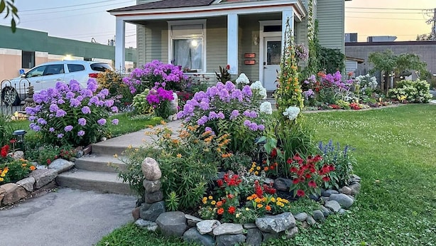 A residential property with a well-maintained garden, a front porch, and a driveway leading to a parked car. - Enjoy the entire main level of this Historic Victorian duplex form the 1800s. Located in the heart of Cambridge. Unwind in private 4-person sauna, king size beds, quaint front porch and fully stocked kitchen. Walk to everything in town. (Cambridge)