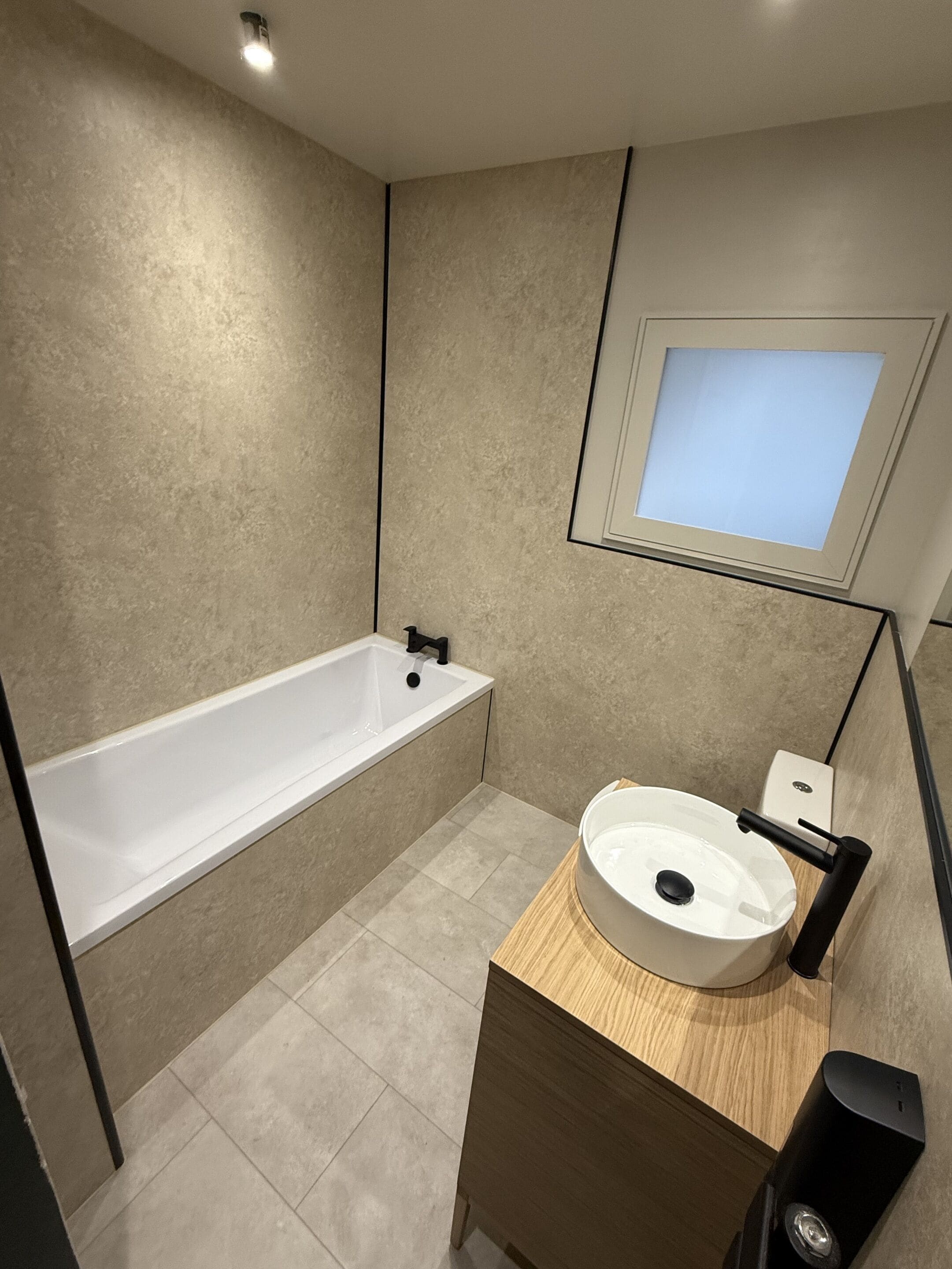A modern bathroom with a bathtub, a sink, and a mirror.
