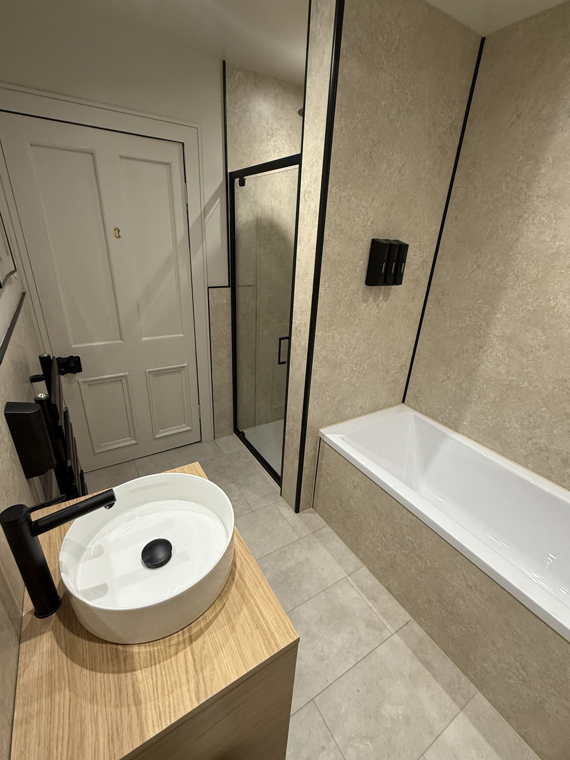A modern bathroom with a round sink, a bathtub, and a glass shower enclosure.