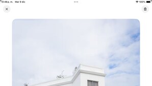 Un bâtiment blanc à la façade symétrique, doté de nombreuses fenêtres et d’une entrée centrale.