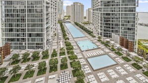 A high-rise residential building with multiple balconies, a central swimming pool, and a landscaped terrace with lounge areas. - ICON 2211 · ★Inredible View -Luxury Unit at the W Brickell★ (Miami)