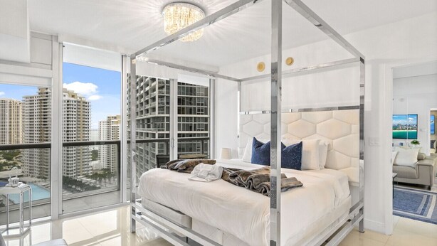 A modern bedroom with a glass four-poster bed, a city view, and a balcony with a pool. - ICON 2211 · ★Inredible View -Luxury Unit at the W Brickell★ (Miami)