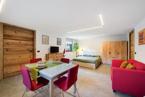 Una habitación moderna con una mesa de comedor, sillas rojas, una cama, un sofá rojo y un armario de madera.