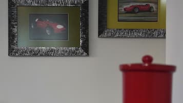 Une pièce avec deux tableaux encadrés accrochés au mur, un objet rouge au premier plan et un meuble en bois.