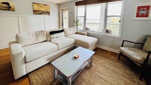 Ein Wohnzimmer mit einer Couch, einem Couchtisch, einem Sessel und einem Fenster mit Blick.