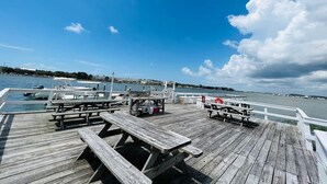 Eine hölzerne Pier mit Picknicktischen und Blick auf das Wasser.