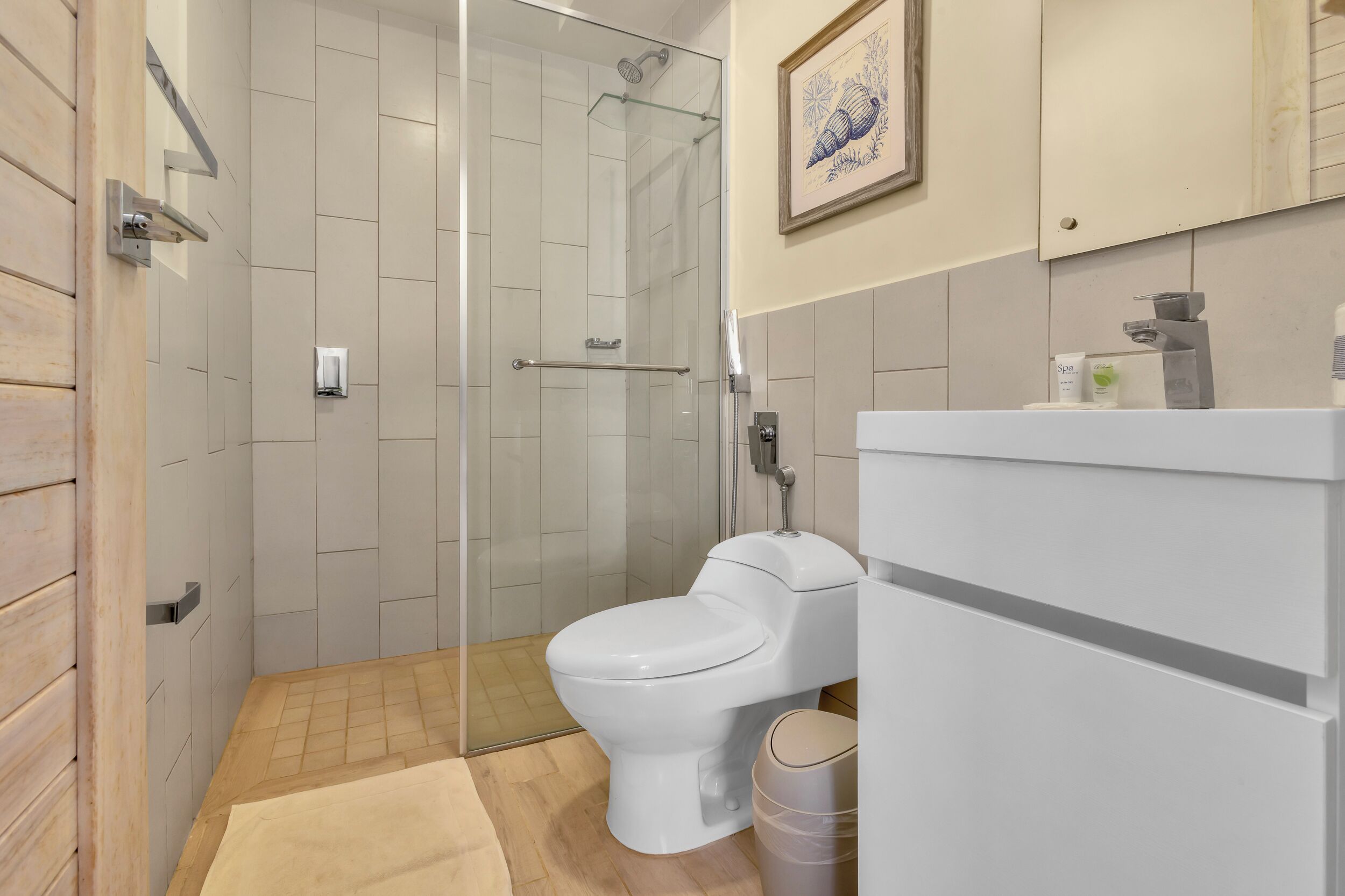 Un baño moderno con ducha de vidrio, inodoro blanco y lavamanos con espejo.
