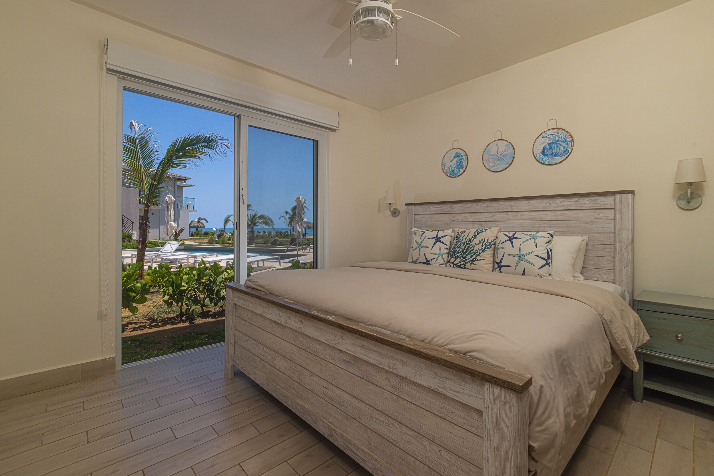 A bedroom with a large bed, a sliding glass door to a balcony, and a ceiling fan.