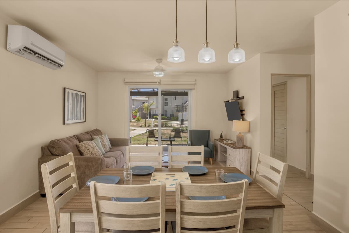 Un comedor con una mesa y sillas de madera, un sofá y una lámpara.