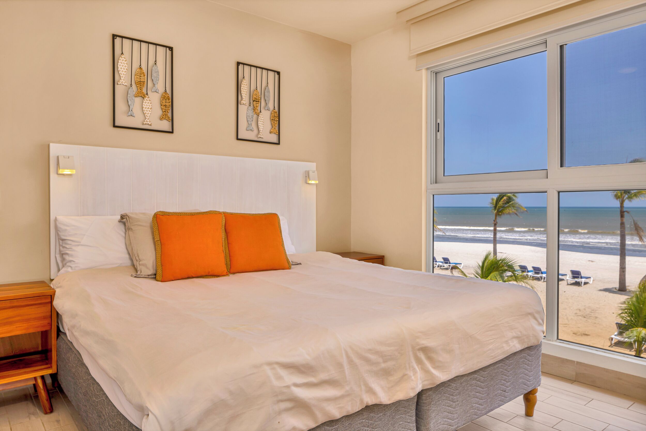 Une chambre avec un grand lit, une table de chevet et une fenêtre donnant sur la plage.