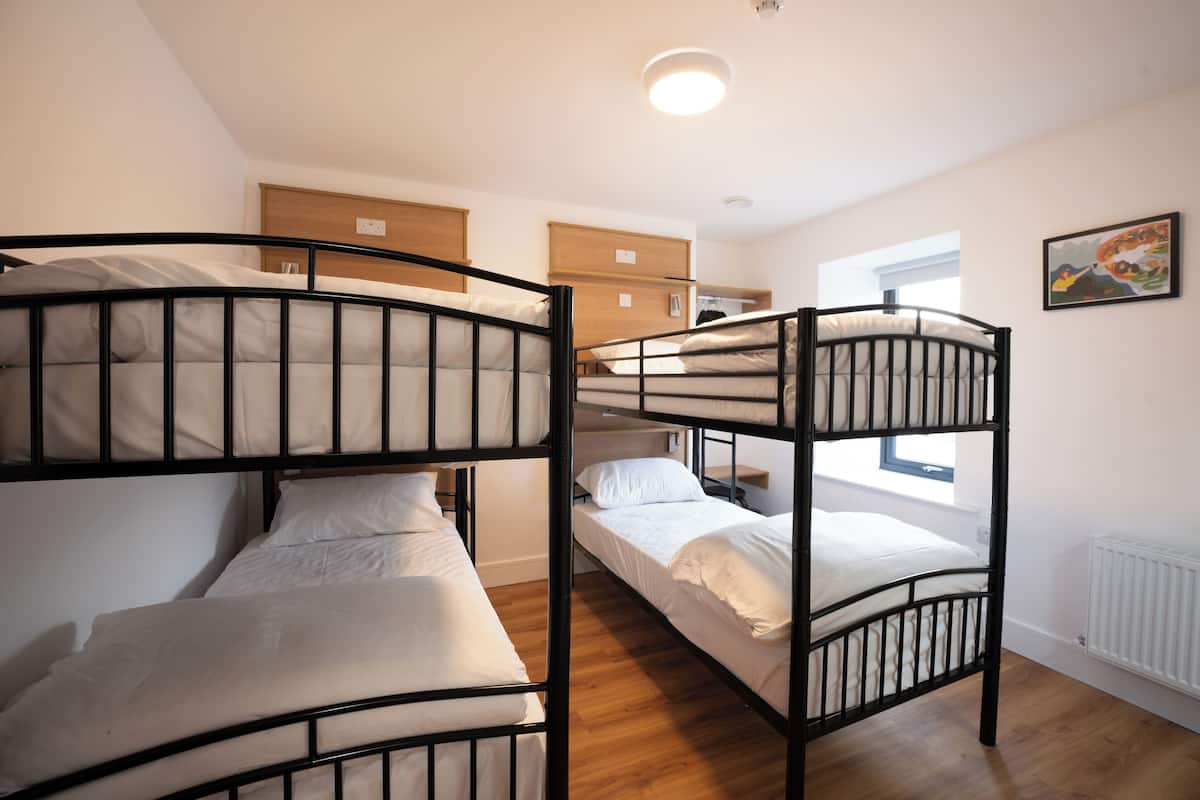 A bunk bed room with a wooden headboard, a small bedside table, and a window with a view.