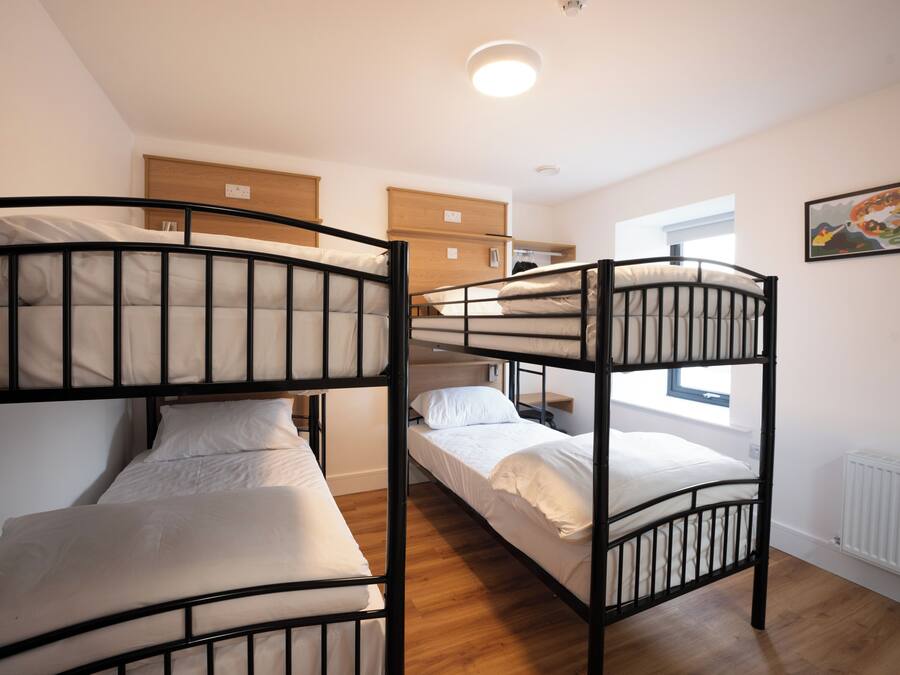 A bunk bed room with a wooden headboard, a small bedside table, and a window with a view.