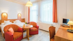 A hotel room with two beds, a dining table with chairs, a TV, and a window with curtains. - Hotel Flora (Bad Harzburg)