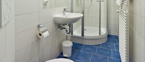 A modern bathroom with a white sink, toilet, and shower.