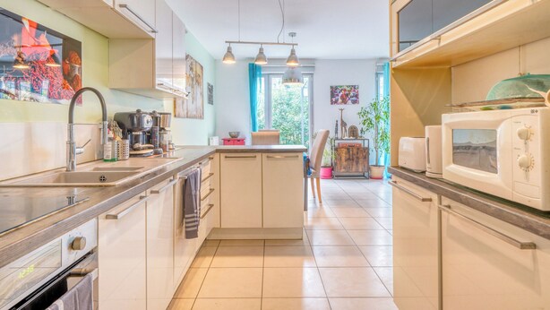 Una cucina moderna con elettrodomestici in acciaio inossidabile, un'isola centrale e vista sul giardino dalla finestra.