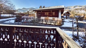 Ein Holzhäuschen mit Balkon, umgeben von verschneiter Landschaft und Bergen.