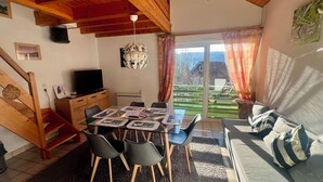 A cozy living space with a dining area, a sofa, and a TV. - Cozy apartment with lake view (Gérardmer)