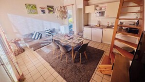 A cozy interior with a dining area, sofa, kitchen, and wooden staircase. - Cozy apartment with lake view (Gérardmer)