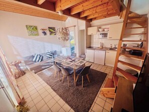 Ein gemütliches Interieur mit Essbereich, einer Couch, einer Küche und einer Holztreppe.