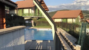 A swimming pool with a diving board, surrounded by buildings with red roofs and a clear sky. - Cozy apartment with lake view (Gérardmer)