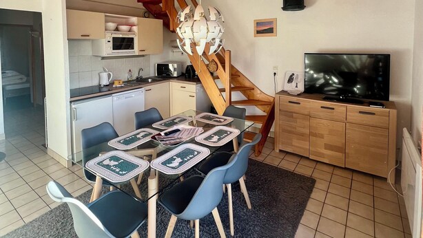 A compact kitchen with a microwave, coffee maker, and a dining area with a table set for four. - Cozy apartment with lake view (Gérardmer)