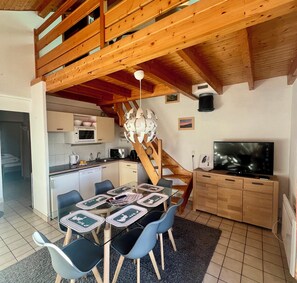 A compact kitchen with a microwave, coffee maker, and a dining area with a table set for four. - Cozy apartment with lake view (Gérardmer)