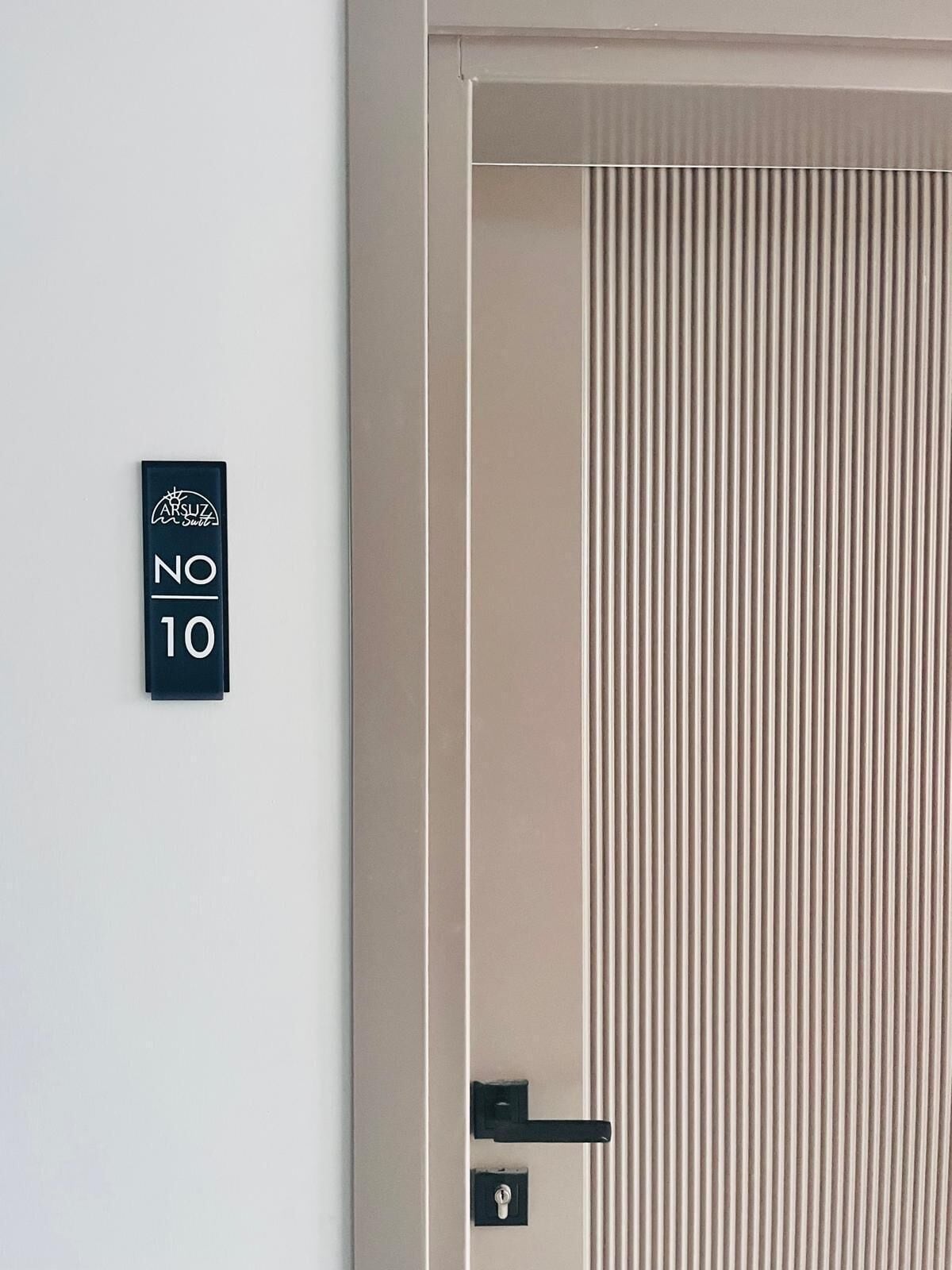 A hotel room door with a vertical striped pattern, a black door handle, and a sign indicating room number 10.
