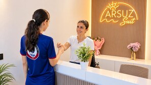Un mostrador de recepción con un letrero de neón que dice 'ARSUZ Suit' y una planta en el mostrador.