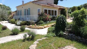 Ein Haus mit Ziegeldach, einem Kiesweg und einem Garten mit verschiedenen Pflanzen und einem kleinen Teich.