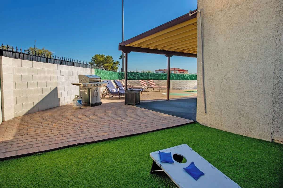 An outdoor patio with a barbecue grill, lounge chairs, and a covered seating area.