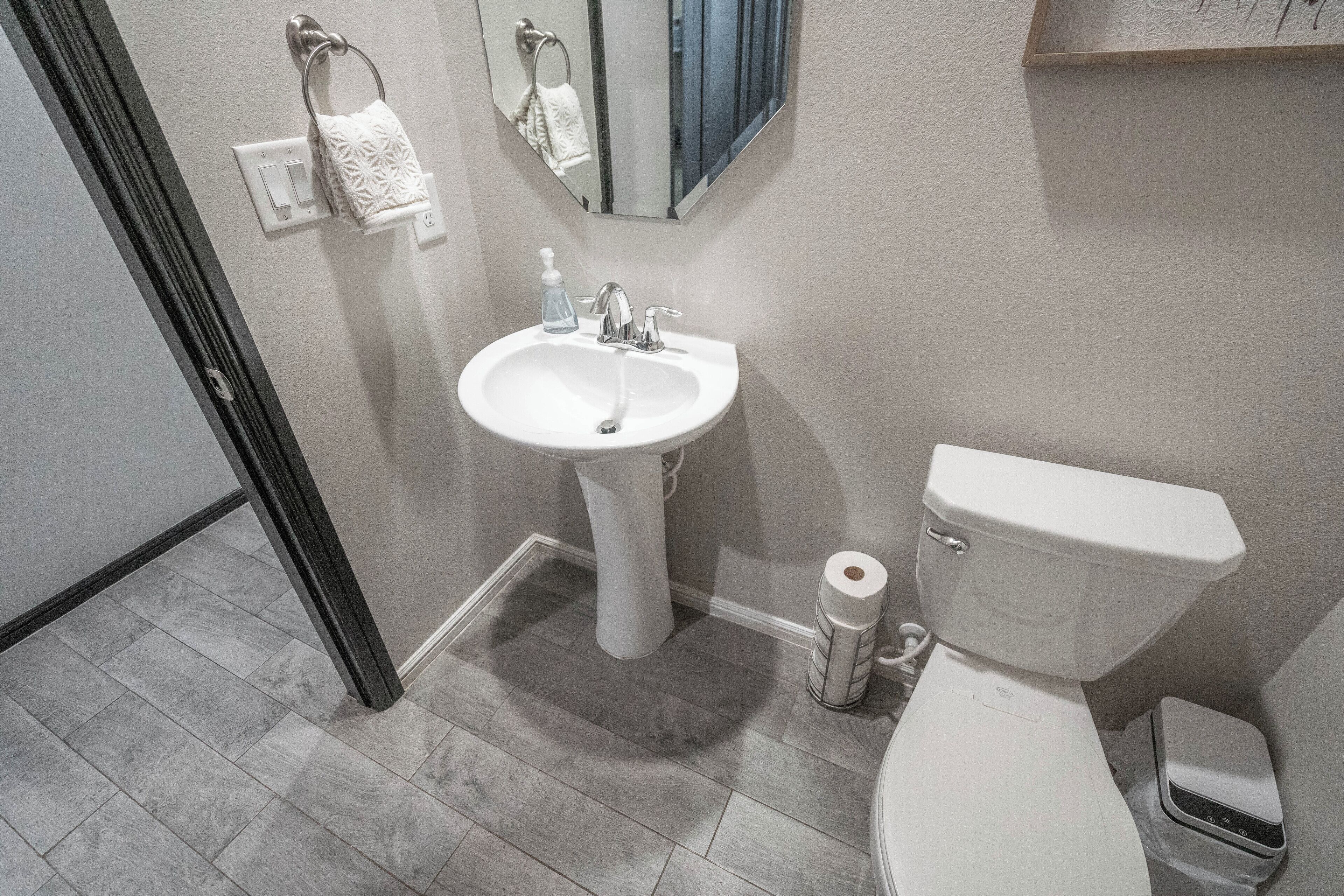 Een badkamer met een witte wastafel, een toilet en een spiegel boven de wastafel.