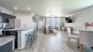 A modern kitchen with a central island, bar stools, and a dining area with a table and chairs.