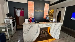 A reception desk with a marble top, flags, and a sign indicating check-out time. - Grand Medya Hotel (Istanbul)
