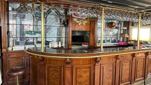 A bar area with a curved wooden counter, glass shelves with bottles, and hanging glassware. - Grand Medya Hotel (Istanbul)