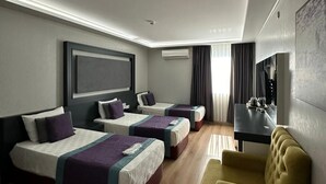 A hotel room with two beds, a sofa, a TV, and a desk. - Grand Medya Hotel (Istanbul)