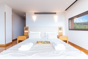A modern hotel room with a large bed, two bedside tables, a tray with breakfast items, and a window with a view of greenery. - Casa Vista Azul by Atlantic Holiday (Santa Cruz)
