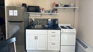 Una cocina compacta equipada con refrigerador, microondas, estufa, lavaplatos y armarios.