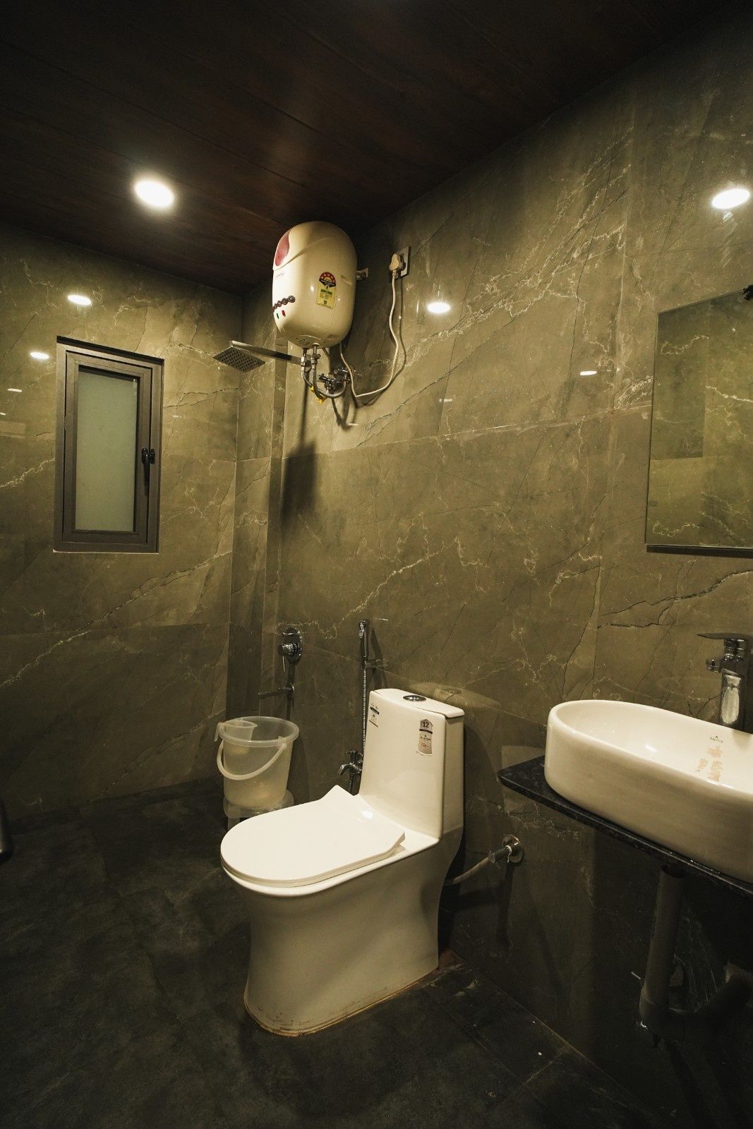 Ein Badezimmer mit Toilette, Bidet und Waschbecken, alles mit Marmorwänden und einer Holzboden.